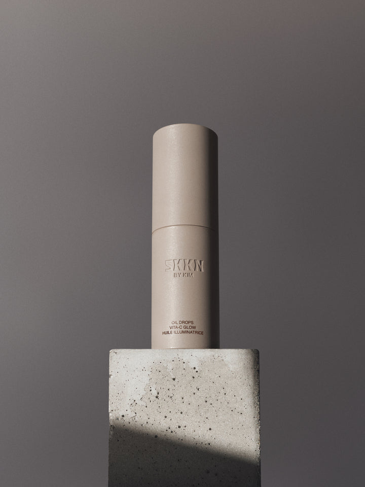 Bottle of SKKN BY KIM Oil Drops C-Vita Glow on stone pedestal