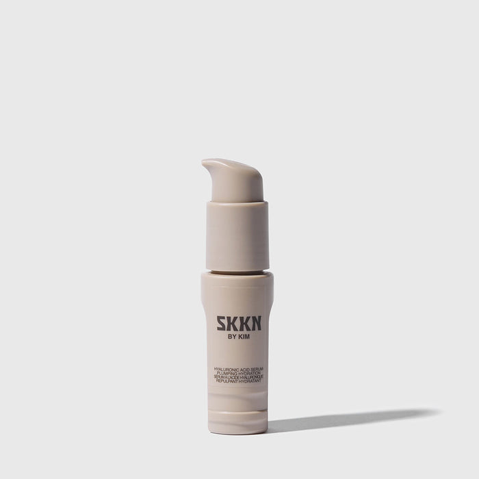 Opened bottle of SKKN BY KIM Hyaluronic Acid Serum Plumping Hydration next to cap